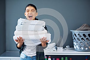 I love clean linen. an attractive young woman carrying a pile of towels while doing laundry at home.