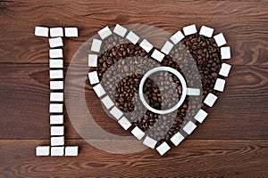 I love coffee. The concept of coffee lover with coffee cup and heart-shaped beans on a wooden background.