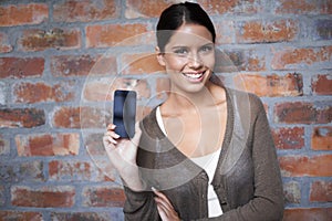 I love this mobi site. Portrait of a young woman holding up the blank screen of her smartphone to the camera.