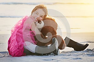 I love my bear. Portrait of a cute little girl playing with her teddy bear on the beach.