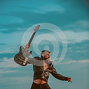 I love my guitar. Bearded man jump with guitar on blue sky. Hipster guitarist with beard on excited face fly in clouds