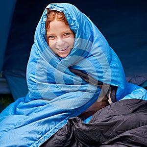 I love my sleeping bag. Portrait of a young girl sitting in her sleeping bag.