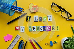 I love my Teacher - text made with carved letters on yellow desk with office or school supplies on pupil table