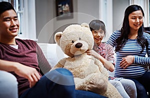 I love my teddy. Cropped portrait of a little girl sitting on the sofa with her teddybear between her parents.