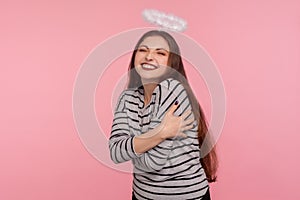 I love myself! Portrait of optimistic attractive happy woman with holy nimbus over head embracing herself