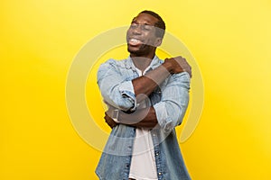 I love myself. Portrait of self-satisfied happy man cuddling himself. indoor studio shot isolated on yellow background