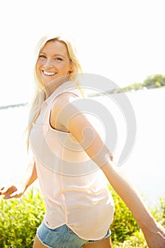 I love the outdoors. Portrait of a smiling young blond woman walking near a lake.