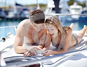 I love this photo. Young couple looking at their holiday snapshots while relaxing on a yacht.