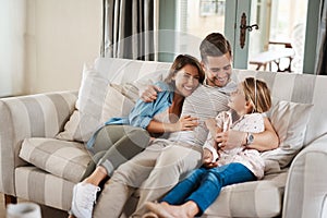 I love seeing my girls happy. an adorable little girl spending quality time with her parents on the sofa at home.