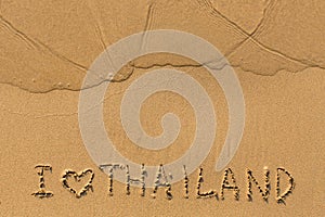 I love Thailand - text written on sandy beach .