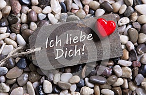 I love you card with german text and a red heart on a wooden sign.