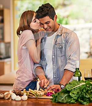 I love it when you cook for me. Shot of a young woman kissing her husband while he prepares dinner.