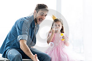 I love you, dad! Handsome young man at home with his little girl are having fun and blowing soap bubbles. Happy Father`s