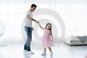 I love you, dad! Handsome young man is dancing at home with his little girl. Happy Father`s Day!