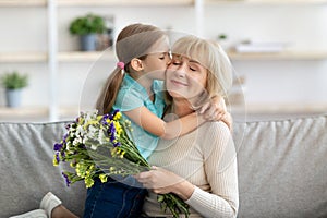 Little girl kissing and greeting woman with flowers