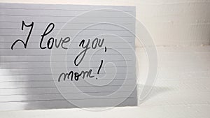 I love you mom writing love text for mother on paper. Label tag with lovely message for mother`s day