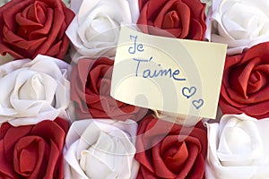 i love you translated in french written on yellow card with colorful rose flowers.