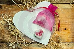 I love you - white, simple heart cut from wood on a romantic, simple rustic background next to two white, hearts shaped chocolates