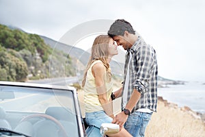 I love you. A young couple sharing a romantic moment on a hilltop after taking a scenic drive.
