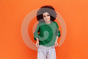 I& x27;m bankrupt. Unhappy poor woman with Afro hairstyle in green sweater showing empty pockets and