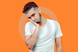 I`m bored, tired of everything. Portrait of brunette man looking at camera with disinterest. indoor studio shot isolated on orang