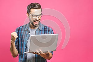 I`m a winner! Happy man holding laptop and celebrating his success over pink background