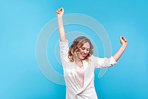 I`m winner! Portrait of ecstatic overjoyed lady dancing with raised arms, smiling excitedly. blue background