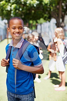 I make the most of school with a confident attitude. Smiling african-american boy wearing his school backpack posing