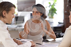 Am I making my point clear. a a group of office workers having a discussion around a table in the office.