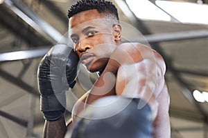 I might punch you in the face if I feel like it. Portrait of a muscular young man wearing boxing gloves in a gym.