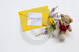 I miss you message card handwriting with yellow envelope, yellow flower ylang ylang and teddy bear