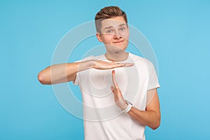 I need break, please! Portrait of worker man in casual white t-shirt showing time out gesture