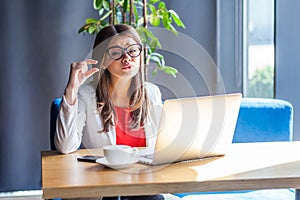 I need a few more. Portrait of hopeful pleased beautiful stylish brunette young woman in glasses sitting, looking at camera and