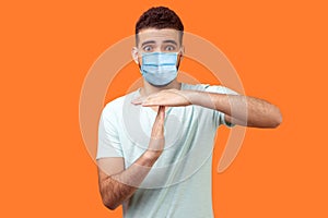 I need more time! Portrait of frustrated brunette man with surgical medical mask showing time out gesture, looking with imploring