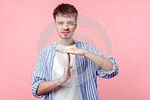 I need more time. Portrait of upset brown-haired man with small beard and mustache showing time out gesture. isolated on pink