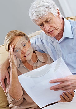 I need my glasses, Im seeing double. a unhappy senior couple looking at documents together.