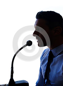 I need to make one thing clear...Sihouette shot of a man in a shirt and tie speaking into a microphone.