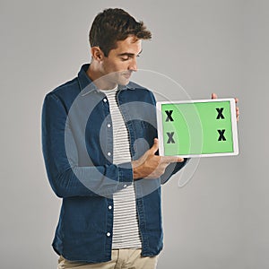 I needed to show you this. Studio shot of a young man holding a digital tablet with a green screen against a grey