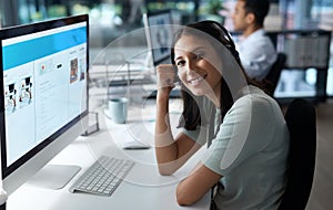 I never miss a call. Portrait of a young woman using a headset and computer in a modern office.