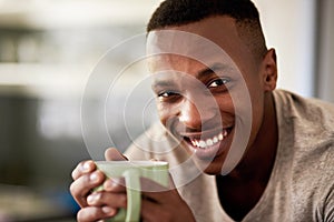 I never start my day without my coffee. Cropped portrait of a handsome young man smiling while having a cup of coffee in