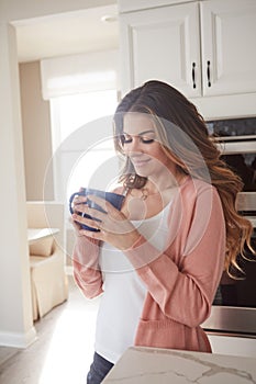 I orchestrate my mornings to the tune of coffee. a beautiful young woman having coffee in the kitchen at home.