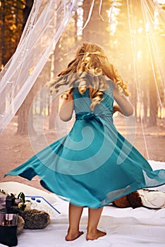 I am the princess of the woods. an unrecognizable little girl dancing underneath her tent outside in the woods.