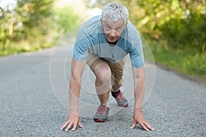 I am ready to start! Confident senior man stands in posture on start, being participant of sport marathon, wears comfortable sneak