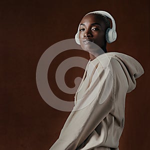I rock to my own beat. Studio portrait of an attractive young woman wearing headphones and posing against a brown