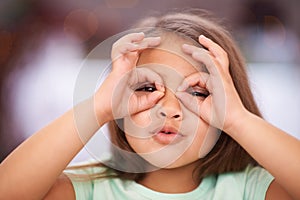 I see you. Shot of a playful little girl with pulling a funny face.