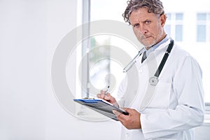 I see your last checkup was five years ago. Portrait of a mature doctor standing in his office and holding a clipboard.