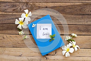 I am sorry message card handwriting on blue diary book with white flowers frangipani ,jasmine