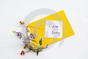 I am sorry message card handwriting with yellow envelope, yellow flower ylang ylang and little purple