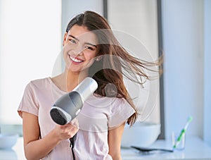 I spend a lot of time taking care of my hair. Cropped portrait of a beautiful young woman blowdrying her hair in the