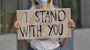 I STAND WITH YOU on cardboard poster in hands of female protester activist. Stop Racism concept, No Racism. Rallies